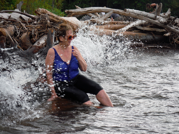 The waves are splashing against the logs and Karen.